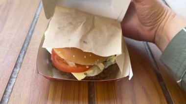 İçinde McDonalds 'ın restoran logosu olan Büyük Lezzetli Kutu. Big Mac 'le eller açık, kadın hamburgeri alıyor ve yiyor. Ukrayna Vinnitsa 07.02.2025