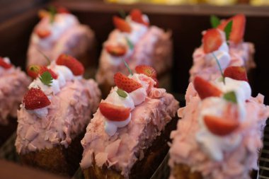 Taze meyve ve ahşap masada çikolata parçalarıyla süslenmiş beyaz çikolatalı çilekli yoğurt pastası. Sevgililer Günü ya da doğum günü partisi için lezzetli ve tatlı pembe çilekli pasta. Ev yapımı fırın.