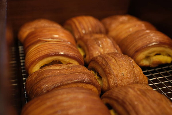 Bakery counter with fresh apple puff pastries. transparent glove picks up a few for purchase. Close-up shot, no face visible. Crispy, golden pastries for food lovers. High quality