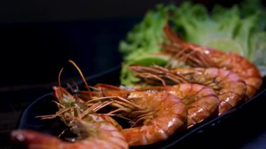 Baharatlı dört pişmiş karides taze marul ve domates dilimleriyle beyaz bir tabakta sıralanarak basit ve sağlıklı bir yemek seçeneği oluşturulur. Üst manzara, genel giderler. Yüksek kalite 4k görüntü