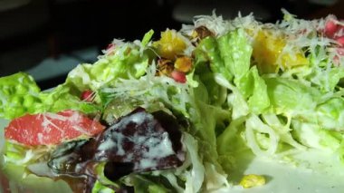 Sebze salatasına mayonez sosu dökülüyor. Mavi arka planda salata soslu taze malzemelerden sağlıklı ve diyet yiyecekler. Ağır çekimde. Yüksek kalite 4k görüntü