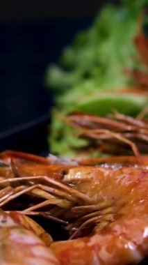 Baharatlı dört pişmiş karides taze marul ve domates dilimleriyle beyaz bir tabakta sıralanarak basit ve sağlıklı bir yemek seçeneği oluşturulur. Üst manzara, genel giderler. Yüksek kalite 4k görüntü