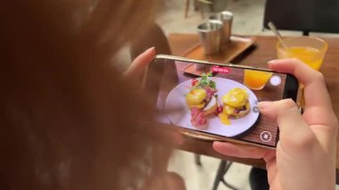 Adam dikey video çekiyor, hikayeler çekiyor, akıllı telefondaki lezzetli restoran yemeklerini sosyal medya için fotoğraf çekiyor. Erkekleri etkileyen çekim klip, film, telefon kamerasında yumurtalı kahvaltı görüntüleri..