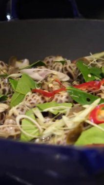 Mutfakta yemek pişirirken bir şefin dilimlenmiş sebzeleri tavaya attığı yakın plan statik çekim. Yüksek kalite 4k görüntü