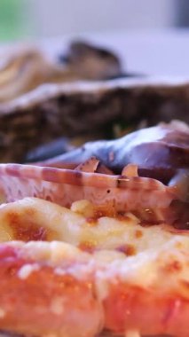 Kırmızı biber soslu çıtır badem kabuklu karidesler, yenilebilir çiçekler ve mikroyeşilliklerle süslenmiş, mavi seramik bir tabakta servis ediliyor. Canlı deniz ürünleri tabağı. 