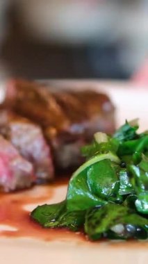 Güneş ışığında taze ıspanak yaprakları, havuç, salatalık ve vişneli domates salatasıyla servis edilen sulu ızgara domuz bifteği. Yüksek kalite 4k görüntü