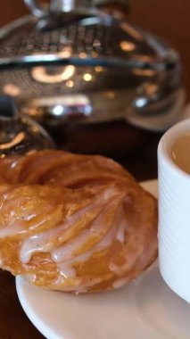 Büyük çikolatalı pasta ve sıcak, dumanı tüten bir fincan sütlü kahve, açık renkli ahşap masa üstünde oturarak el yapımı fincana dökülüyor. Yüksek kalite 4k görüntü