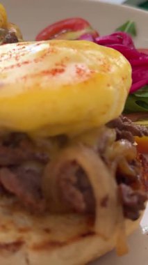 Kadın kahvaltıyı yumurta, taze sebze ve meyve ile dengeli bir şekilde yiyor. Sağlıklı beslenme ve yaşam tarzını destekleyen besleyici bir sabah yemeği. Yüksek kalite 4k görüntü