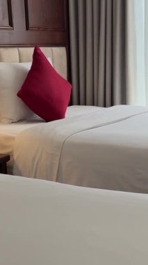 Yetişkin bir kadın beyaz bir bornozla yatağa uzanıyor pencerenin yanında dinleniyor, elinde telefonla sosyal ağlarda oturuyor. Yüksek kalite 4k görüntü