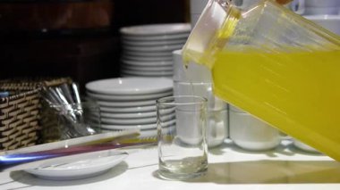 Kadın meyve sıkacağını renkli arka planda cama portakal suyu dolduruyor. Kafede turunçgil vitamik sağlıklı meyve suyu, sabah kahvaltısı içeceği. Yüksek kalite 4k görüntü