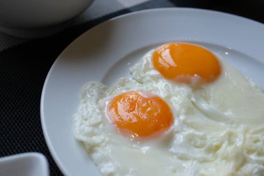 Biberli kahvaltı tabağı, beyaz tabakta kızarmış yumurta ve vişneli domates, yeşil kareli peçeteyle sarı zemin, sağlıklı beslenme kavramı, sabah yemeği.