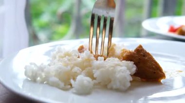 Kişi çatal ve kaşık kullanarak tavuk eti ve buharda pilav yiyor. Manzarayı kapat. Yüksek kalite 4k görüntü