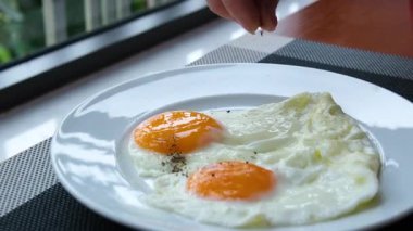 Yumurtaya karabiber serpin. Yumurtalı el çeşnisi. Çiğ yumurta karabiber serpiştirilir. Şeffaf beyazın altında yumurta sarısı. Yüksek kalite 4k görüntü