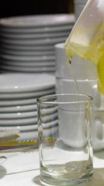 Kadın meyve sıkacağını renkli arka planda cama portakal suyu dolduruyor. Kafede turunçgil vitamik sağlıklı meyve suyu, sabah kahvaltısı içeceği. Yüksek kalite 4k görüntü