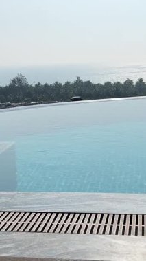 Sakin çatı sonsuz havuzu çarpıcı bir günbatımının canlı renklerini yansıtır, sakin ve huzurlu bir atmosfer yaratır rahatlama ve lüks seyahat için mükemmel, havuz üzerinde huzurlu bir gün batımı.