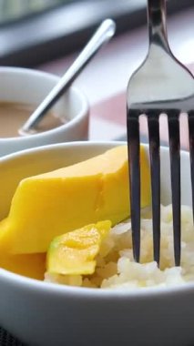 Ahşap zemin üzerinde mangolu tatlı pilav. Mango Asya 'da popüler bir tropikal meyvedir. Yapışkan pirinç ve hindistan cevizi sütüyle servis edilir. Seçici odak ve ücretsiz kopyalama alanı. Sanayi.