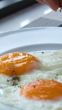 Yumurtaya karabiber serpin. Yumurtalı el çeşnisi. Çiğ yumurta karabiber serpiştirilir. Şeffaf beyazın altında yumurta sarısı. Yüksek kalite 4k görüntü