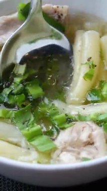 Buhar tüten bir kase Pho, geleneksel bir Vietnam şehriye çorbası, taze otlar, acı biberler ve sığır köfteleriyle süslenmiş. İştah açıcı et suyu ve canlı malzemeler lezzetli bir görsel yaratıyor..