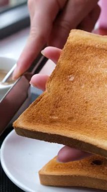 Bir kadın tostun üzerine tereyağı sürüyor, yakın plan. Yüksek kalite 4k görüntü