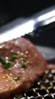 Kırmızı kral karidesler kalın bifteklerin yanında sıcak ızgarada cızırdıyor. Bir aşçı eti ızgaraya atmak için metal maşa kullanır. Açık ateşte sulu deniz ürünleri ve sığır eti. Lezzetli bir sörf karışımı..