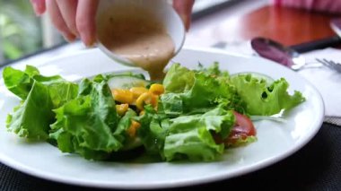 Sebze salatasına mayonez sosu dökülüyor. Mavi arka planda salata soslu taze malzemelerden sağlıklı ve diyet yiyecekler. Ağır çekimde. Salatanın üstüne sos dök