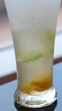 Limonlu ve buzlu bir bardak soda. Köpüklü su, buzlu ve limonlu bardağa dökülür. Dönen masanın yakın çekim görüntüleri. Yüksek kalite 4k görüntü