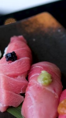 Geleneksel Japon mutfağının en iyi manzarası. Somon, ton balığı ve sebzeli suşi ruloları siyah taş masada servis edilir. Siyah taş üzerinde yemek çubuklarıyla Asya yemekleri. . 