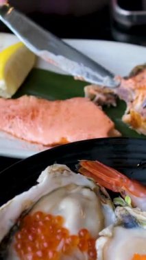 Büyük bir ızgara kırmızı balık filetosu beyaz bir tabakta servis edilir, yanında da iki limon dilimi, yakın plan. Çatal ve bıçakla balığı kes. Yüksek kalite 4k görüntü