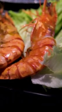 Baharatlı dört pişmiş karides taze marul ve domates dilimleriyle beyaz bir tabakta sıralanarak basit ve sağlıklı bir yemek seçeneği oluşturulur. Üst manzara, genel giderler. Yüksek kalite 4k görüntü