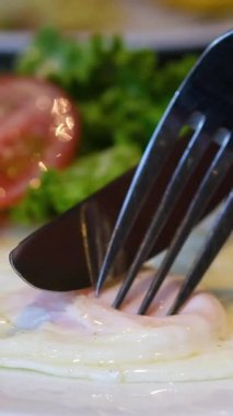 Tabakta çatalla kiraz domatesi delmek. Beyaz tabakta domatesli sahanda yumurta ve sarı arka plan. Sağlıklı kahvaltı konsepti, sabah yemeği. Çatal yumurta domates.