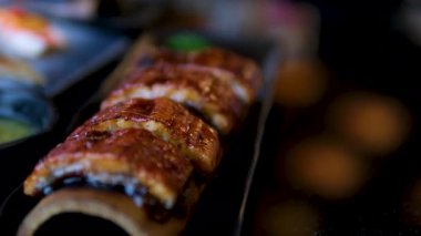 Suşi yılan balığı tabağı Şef renkli suşi rulosu mikroyeşillik ve sosla profesyonel bir mutfakta, ton balığı, avokado, yılan balığı ve somon sosu içeriyor. Yüksek kalite 4k görüntü