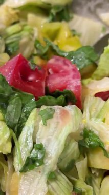 Çatal kullanarak kadın ellerini kapat ve cam kaseden renkli bir salatayı mutfak masasındaki mavi bir tabağa servis et, sağlıklı beslenme alışkanlıklarını teşvik et. Üst manzara, genel giderler. Yüksek kalite 4k görüntü