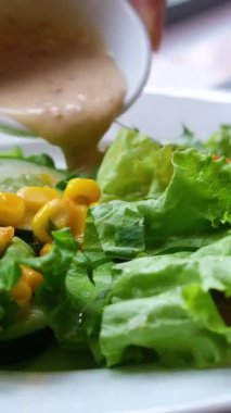 Sebze salatasına mayonez sosu dökülüyor. Mavi arka planda salata soslu taze malzemelerden sağlıklı ve diyet yiyecekler. Ağır çekimde. Salatanın üstüne sos dök