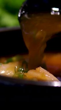 Bir kase ev yapımı tavuk çorbası haşlanmış yumurta, sebze ve taze otlar. Bir kaşık kasenin içinde duruyor. Kaynamış yumurtayla birlikte bambu hasırında servis edilen doyurucu ve sağlıklı bir yemek. Diyet tavuk çorbası.