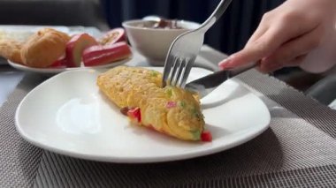 Omleti kesen çatal ve bıçağın yakın çekimi ve tabakta güneşli yumurtalar. Yüksek kalite 4k görüntü