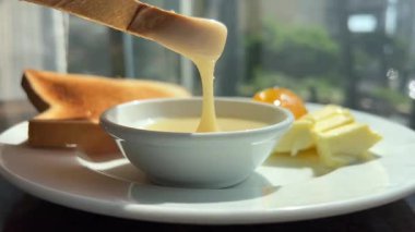 Tereyağlı Fransız tostu, yoğunlaştırılmış süte bir kızarmış ekmek. Lezzetli tostun üzerine şurup dökülüyor. Karışık böğürtlen ve akçaağaç şurubuyla yumurtalı ekmek. Yüksek kalite 4k görüntü