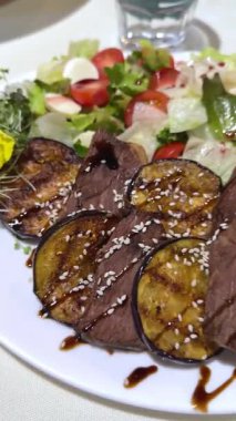 Krema soslu tavuk ciğeri, kızarmış patates, mantar ve seçkin bir restoranda kahverengi ahşap bir masada beyaz porselen bir tabakta karışık yeşil salata. Yakın plan. Yüksek kalite 4k