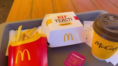McDonald 's Big Mag, Big Tasty, patates kızartması, kahve, restoranda yemek yiyen kadın, dışarıda sarı şemsiyenin altında tepside yemek. Ukrayna, Vinnytsia, 09.22.2025