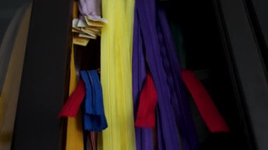 Terzi atölyesindeki çok renkli kumaş fermuarları, farklı uzunlukta, dikiş ve onarım için fermuar formları ve boyutları, terzi için gerekli malzemeler. Terziler için fermuar.