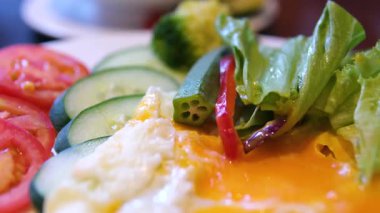 yuvarlak tabak kahvaltı atmosferi yaratır. Yumurta ve kiraz domatesleri, keto diyet dekorasyonunun elementleri olarak servis edilir. Yüksek kalite 4k görüntü