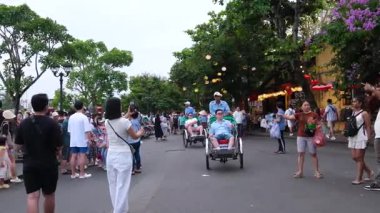 Hoi 'nin Riverside Mahallesi. Japon köprü arabaları ile Vietnam. Sokaklarda turistler geziyor, yerel kafeleri keşfediyor ve otantik kültürel yaşam tarzının tadını çıkarıyor.
