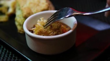 Los Angeles, Kaliforniya 'da çatalla kaplanmış kırmızı soslu tavuk toplama sahnesi. Bir restoranda çatal ve bıçakla yenen siyah bir tabakta kızarmış kanatlar.