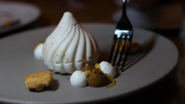 Krem şanti, taze çilek, nane yaprağı ve çatal ve bıçağın yanında koyu dokulu bir yüzey üzerinde dinlenen gül yapraklarıyla kaplı güzel bir pavlova pastası. Yüksek kalite 4k görüntü