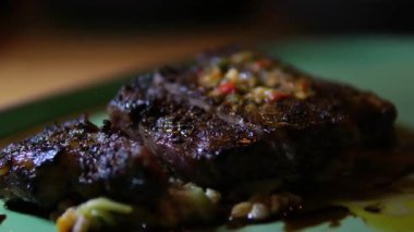 Hafif dilimlenmiş biftek orta pişmiş buğday lapası ıspanak yağı ve yeşil tabakta biraz siyah sos ile servis edilir..