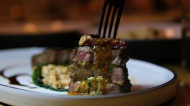 Siyah eldivenli şef yeni pişmiş bifteği bıçakla dilimliyor. Aşçı mutfak tahtasına sıcak bir parça et koyar. Yakın plan. 4k