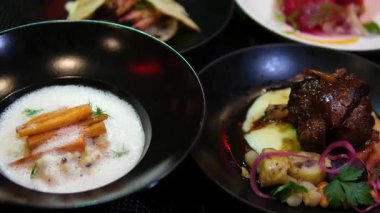 Siyah tabakta kuzu etli gurme yemek masası kremalı patates püresi, beyaz köpüklü havuç, pancar kökü ve hamur köftesi modern tarzda servis ediliyor..