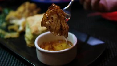 Baharatlı biber sosuna batırılmış taze et ve siyah tabakta çatal damlayan damla damla damla leziz gurme protein aperatifi. Yemek fotoğrafçılığını kapat..