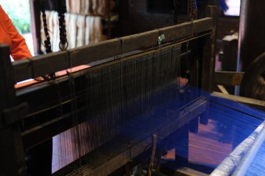 Cinematic video of silkworms hatching, feeding on mulberry leaves, spinning cocoons, and silk threads being reeled and woven into traditional Vietnamese textiles.