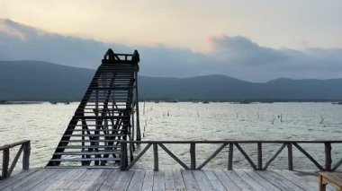 Sakin denizin üzerinde merdiveni ve manzaralı ahşap iskele mavi gökyüzünün altında dağlarla çevrili sakin tropikal manzara Phu Quoc Vietnam.