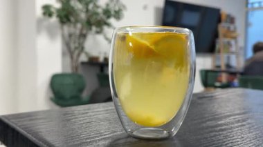 Çift duvarlı cam bardak dolu su taze portakal ve limon dilimleri ve deniz dikenli üzümler içerir. C vitamini antioksidan açısından zengin parlak narenciye renkleri salgılar ve sağlıklı doğal içeceği tazeler..